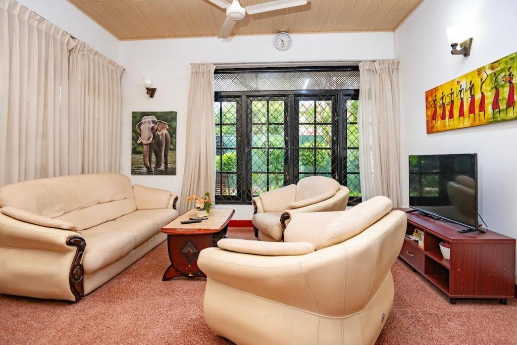 ein Wohnzimmer mit zwei Sofas und einem Flachbildfernseher in der Unterkunft Omni Holiday Bungalow in Mount Lavinia