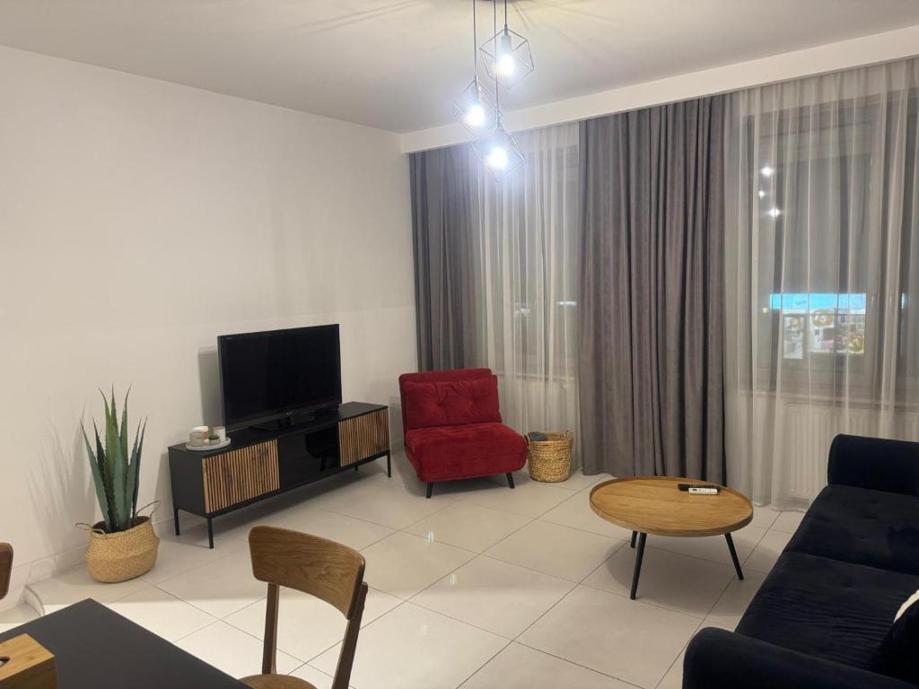 a living room with a red chair and a tv at Apartament Noniewicza 95 in Suwałki