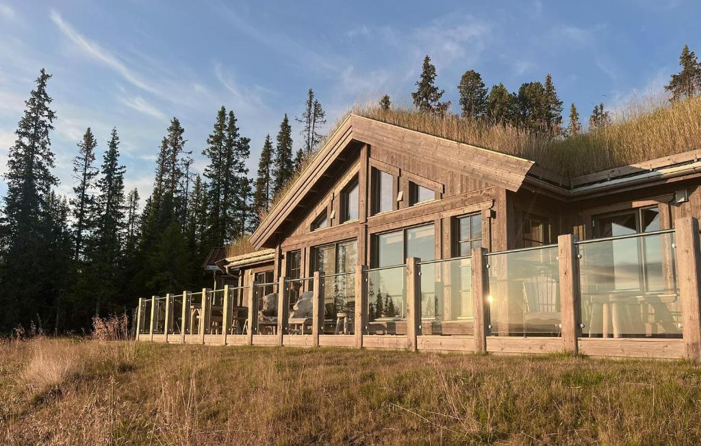 a large wooden house with glass windows in a field at Amazing Home In Gålå With Sauna in Gålå