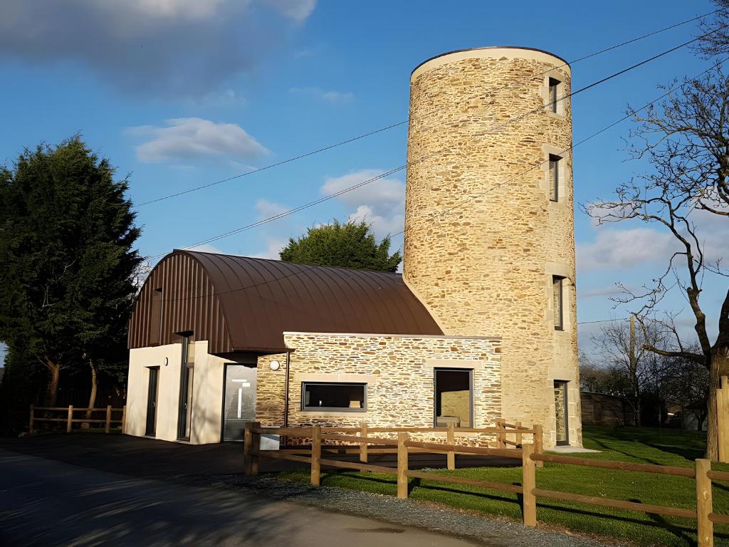 a barn with a brick tower and a wooden fence at Gîte Du Moulin De La Violaye in Fay-de-Bretagne