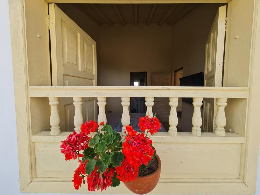 a vase with red flowers sitting on a balcony at Habitación con baño privado in Barichara