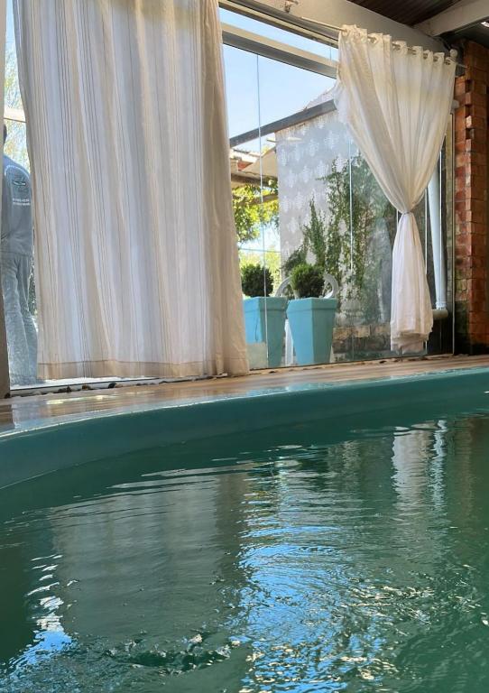 a swimming pool with a white curtain and some water at Hospedagem 1 studio & suites Patricia Tennis in Abelardo Luz