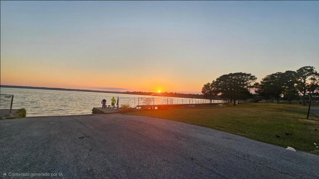 a sunset over a body of water with a pier at Maple House w-Private Jacuzzi Near IAH in Humble