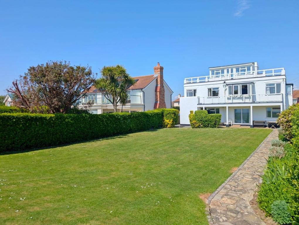 ein großes weißes Haus mit einem Rasen davor in der Unterkunft The Owl - Felpham in Middleton-on-Sea