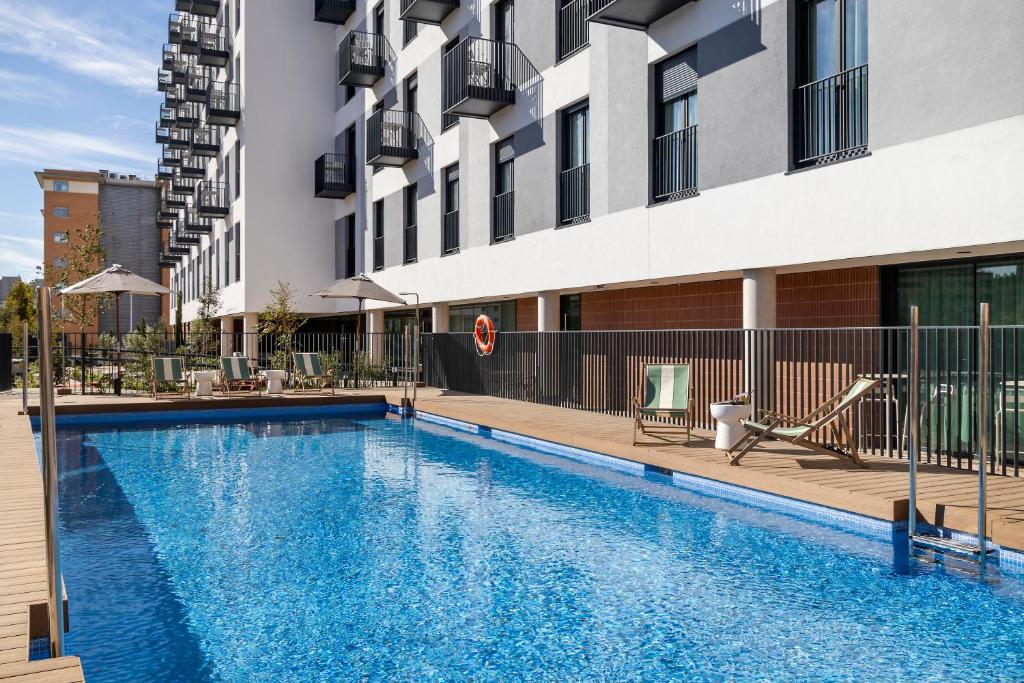 a swimming pool in front of a building at Calido Las Tablas in Madrid