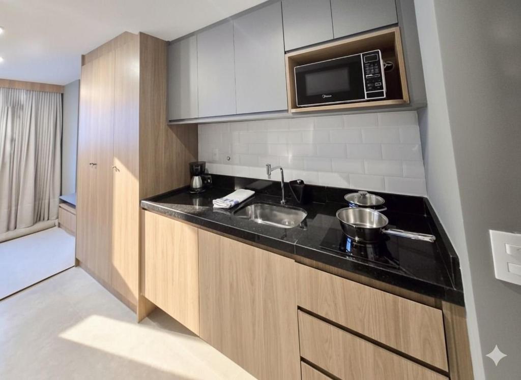 a kitchen with a sink and a microwave at A7 Vix by Housi – studios e apartamentos modernos em Vitória in Guajuru