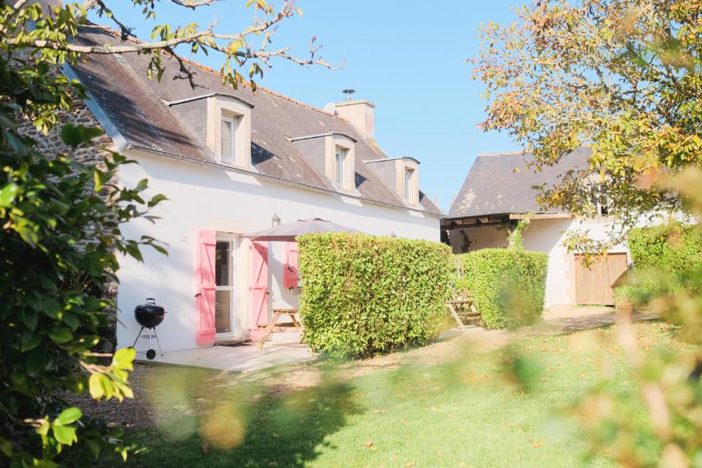 a white house with a red door and a yard at Les Gîtes du Vallon du Trunvel in Plonéour-Lanvern