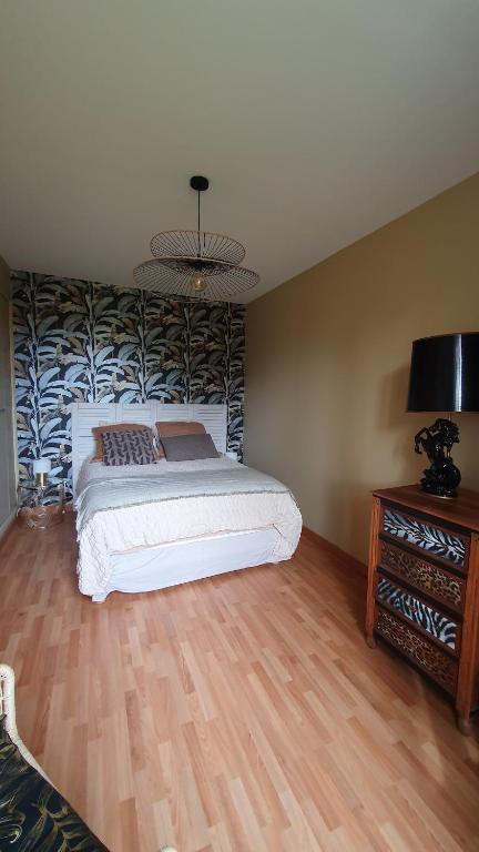 a bedroom with a bed and a table with a lamp at Longère chez Martine et Julie in Romorantin