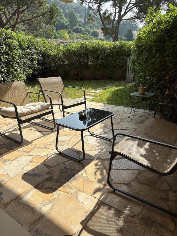 três cadeiras e uma mesa num pátio de pedra em Le Cocon de Vence - Piscine Free Parking em Vence
