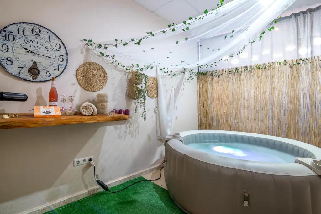 a bath tub in a room with a clock on the wall at El Rincón de Doñana in Villamanrique de la Condesa