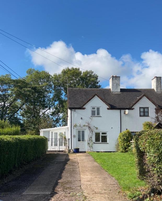 a white house with a driveway at Goosemoor Cottage in Longdon