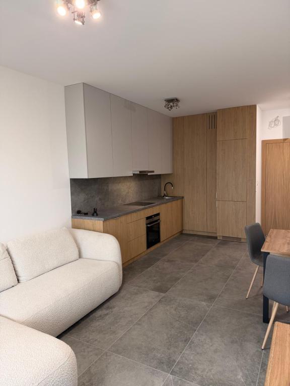 a living room with a white couch and a kitchen at Królewska 51 in Tuszyn