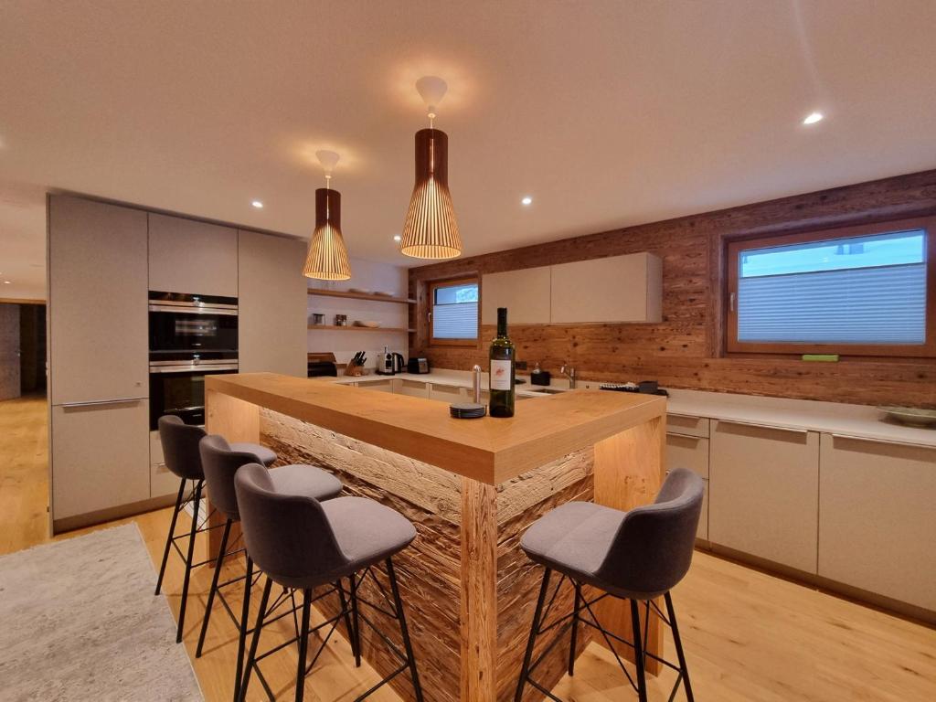 Una cocina con una gran isla con taburetes de bar. en Berghof 2nd Floor, en Saas-Fee