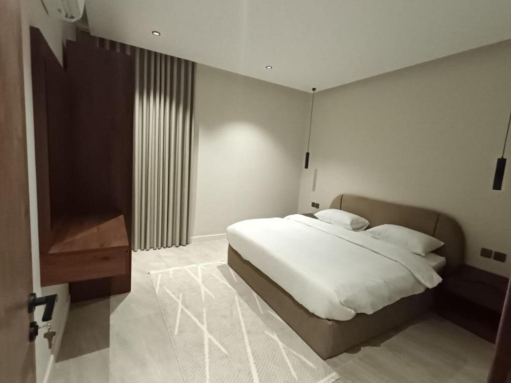 a bedroom with a white bed and a wooden cabinet at روز فيلا in Al Madinah