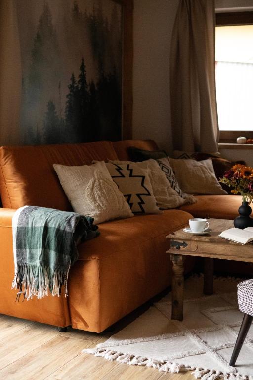 an orange couch in a living room with a table at RELAS - przytulny domek z dwoma sypialniami i antresolą oraz JACUZZI in Murzasichle