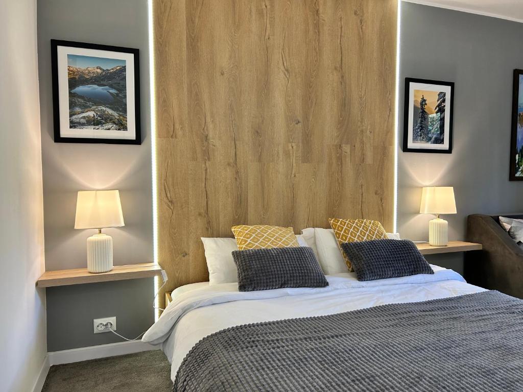 a bedroom with a large bed with two lamps at Devonshire Lodge Chalet in Bansko