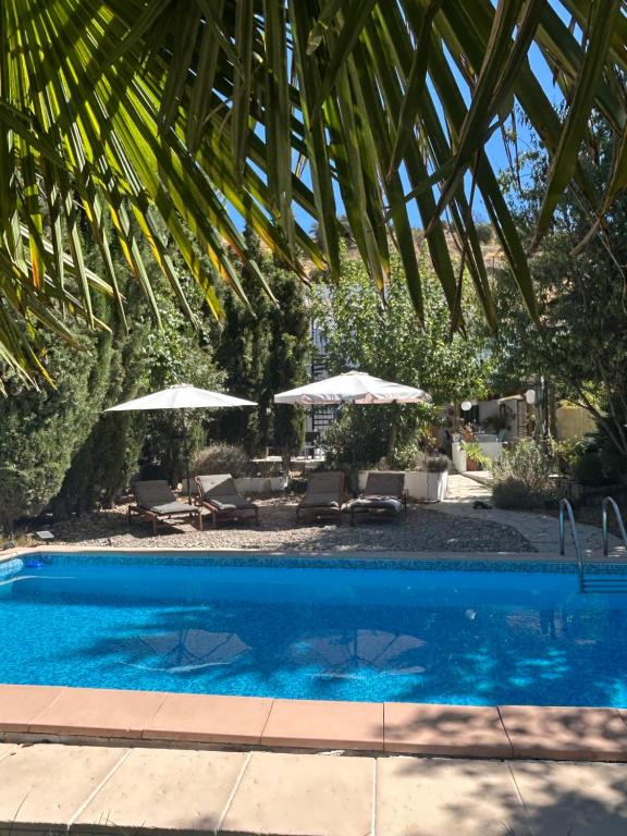 een blauw zwembad met parasols en stoelen bij Casa La Nuez in Almedinilla