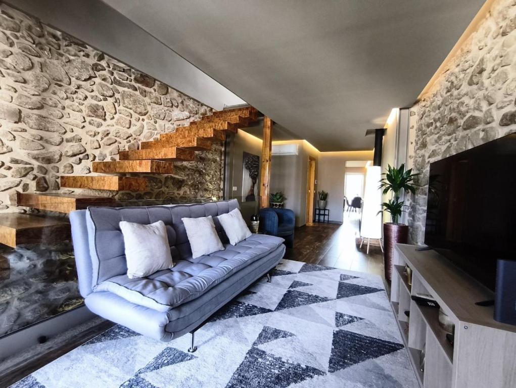 een woonkamer met een bank en een stenen muur bij Refúgio da Nau in Vila do Conde