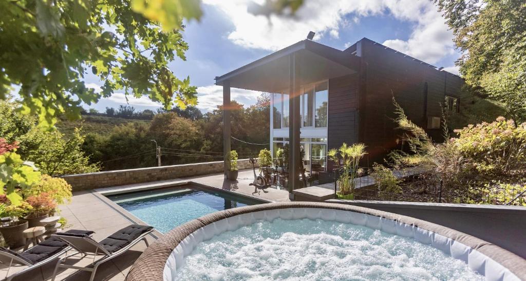 a backyard pool with a hot tub and a house at The White House in Theux