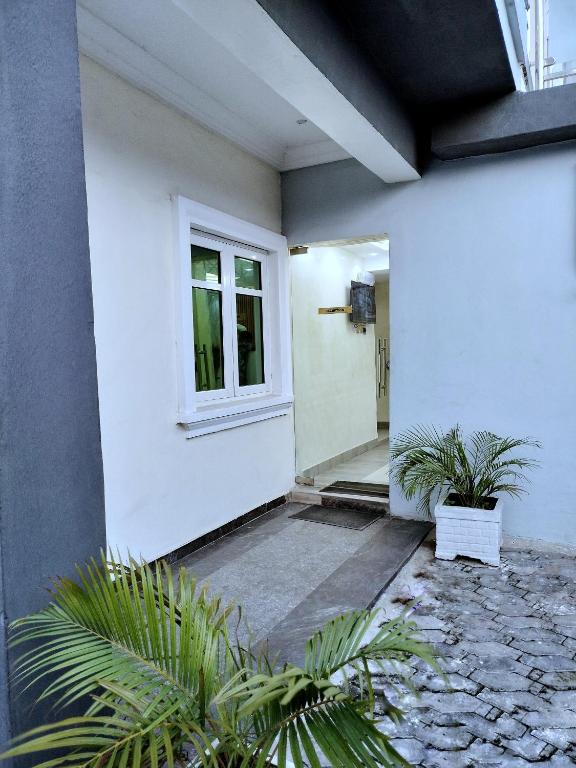a white house with a door and two plants at UG shortlet apartment in Isagatedo
