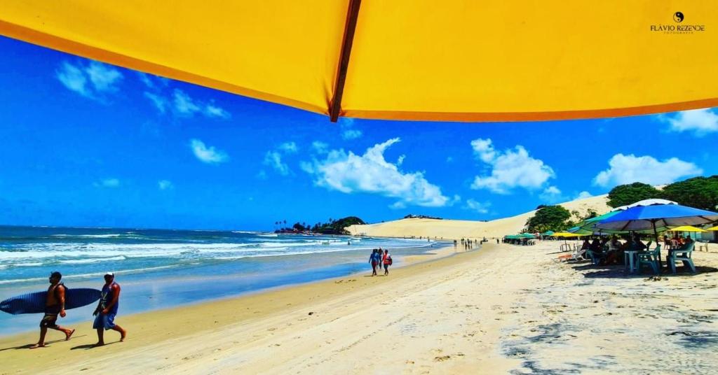 um grupo de pessoas caminhando na praia em Sejam bem vindos, ao paraíso de Genipabu! em Genipabu