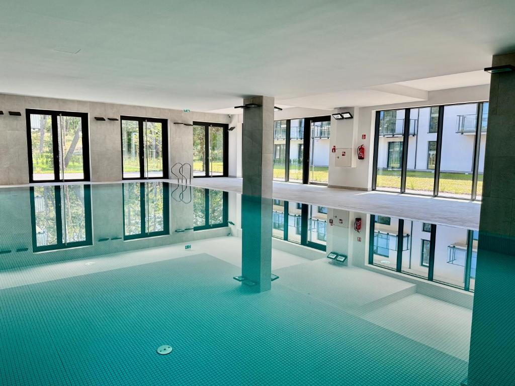 an empty swimming pool in a building with windows at Rezydencja Niechorze 124 z Ogródkiem, Basenem i SPA Gratis - 5D Apartments in Niechorze