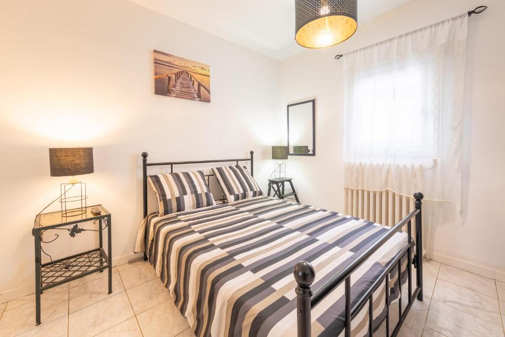 a bedroom with a bed with striped sheets and a window at Chambre calme, zen & lumineuse in Sevran