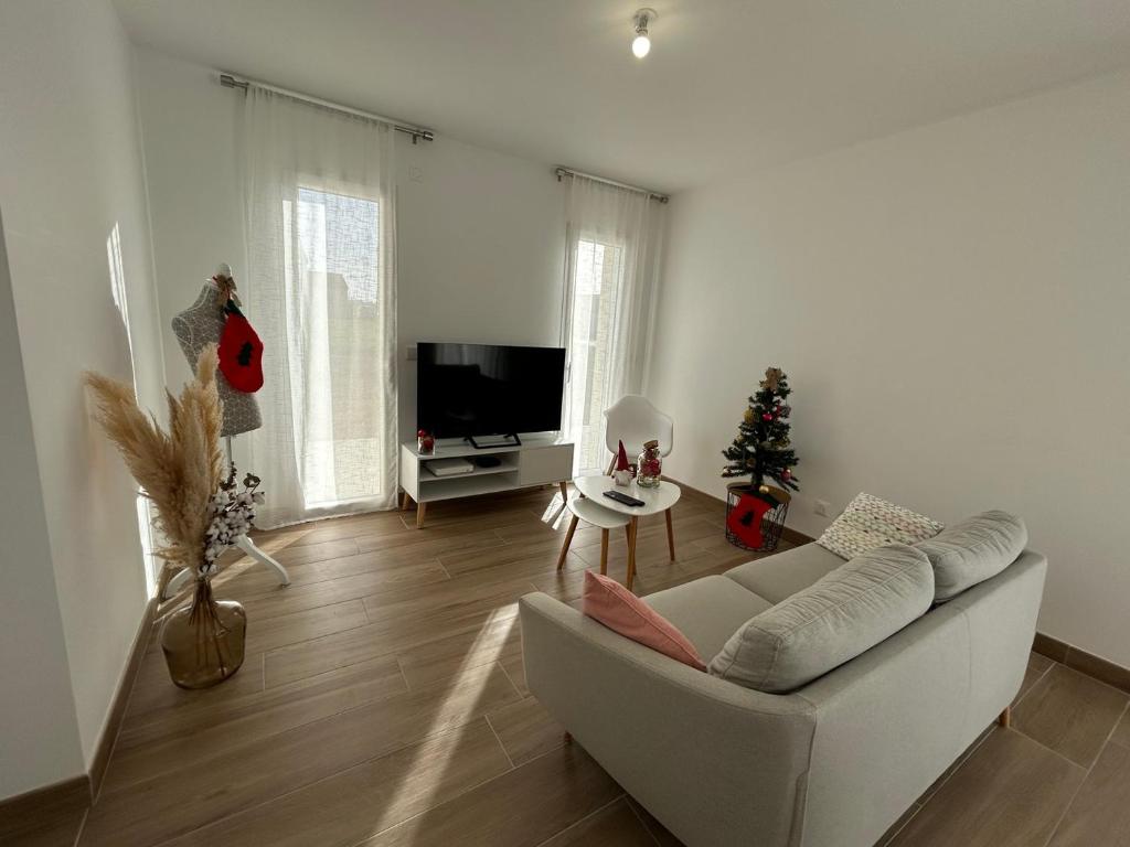 a living room with a white couch and a christmas tree at Pavillon "Le Mexico" - 8 min Futuroscope in Saint-Georges-lès-Baillargeaux