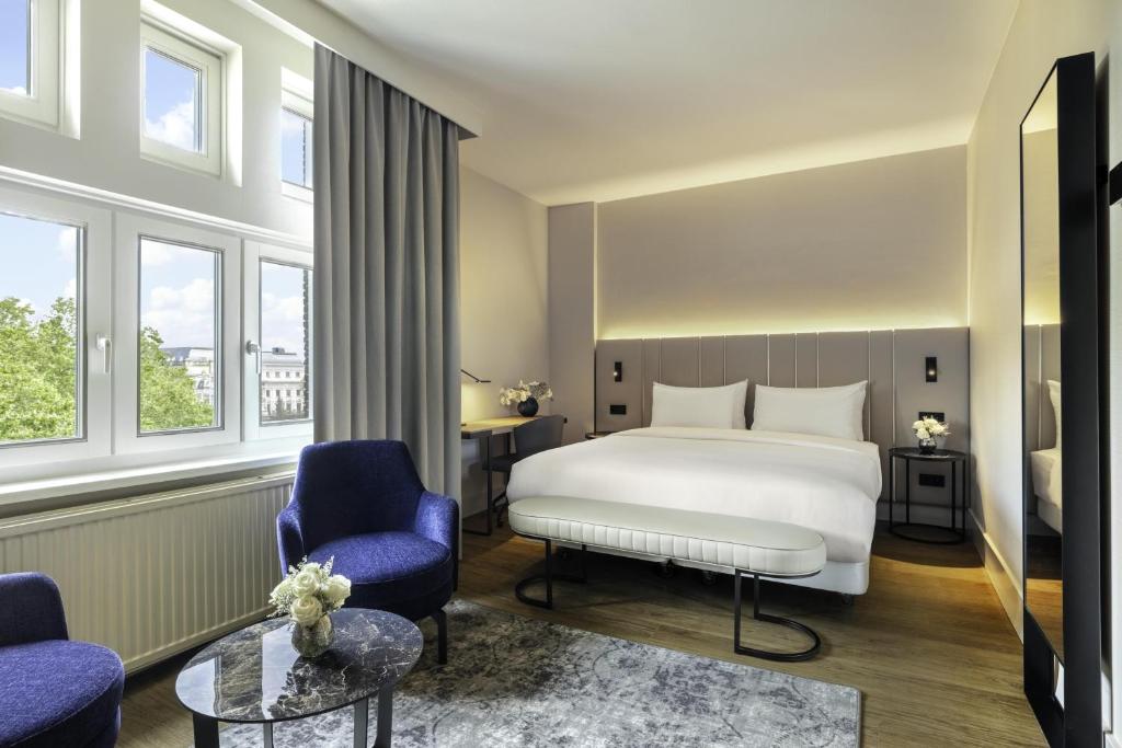 a bedroom with a bed and two chairs and a table at NH Amsterdam Leidseplein in Amsterdam