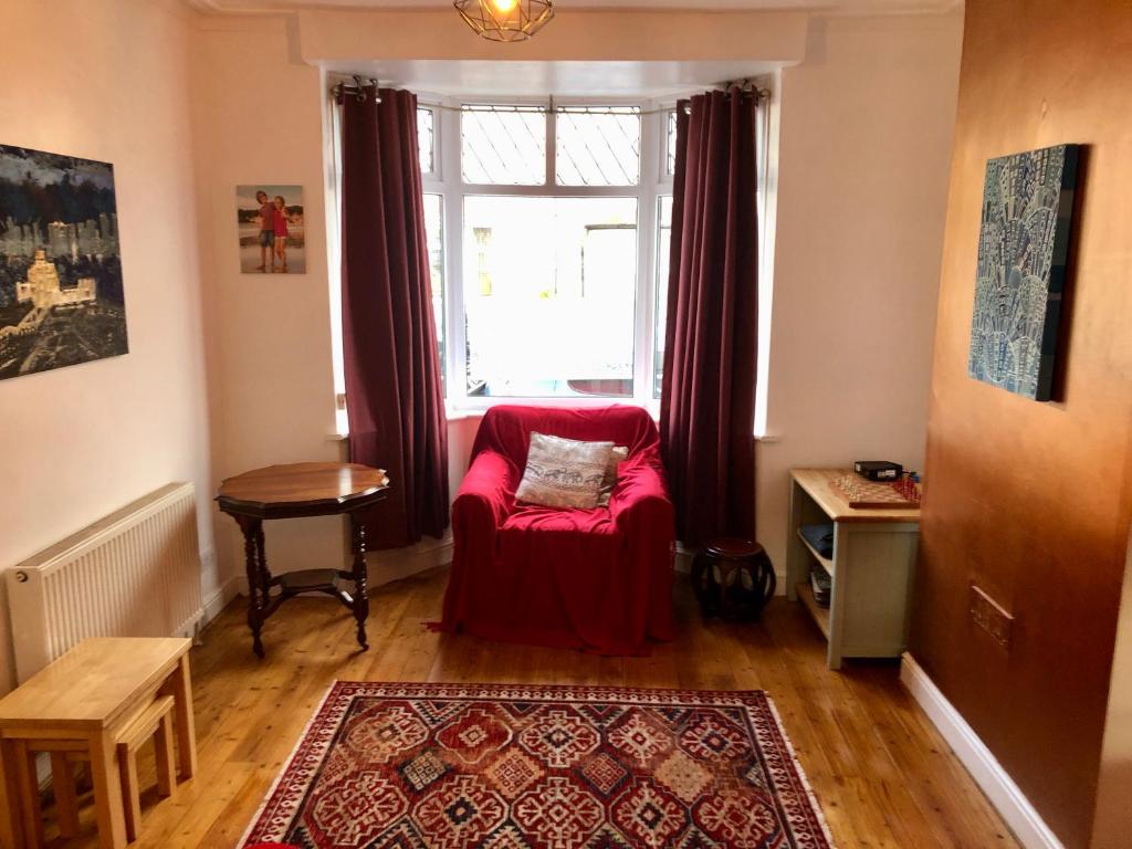 Una sala de estar con una silla roja frente a una ventana. en Trendy Terrace, en Bristol