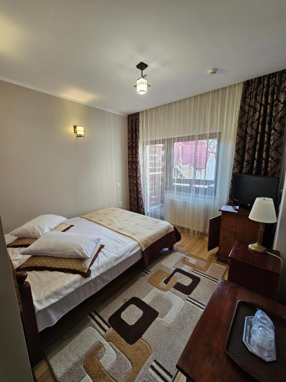 a bedroom with a bed and a table and a television at Pensiunea Mușatinii in Putna