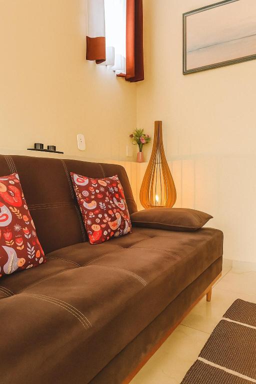 a brown couch in a living room with a vase at Casa Familiar 2 quartos em Búzios in Búzios