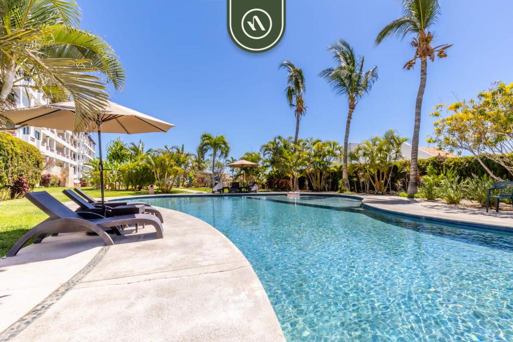 ein Swimmingpool mit zwei Stühlen und einem Sonnenschirm in der Unterkunft New 2 BR Condo in San Jose - Pool - Tennis in San José del Cabo