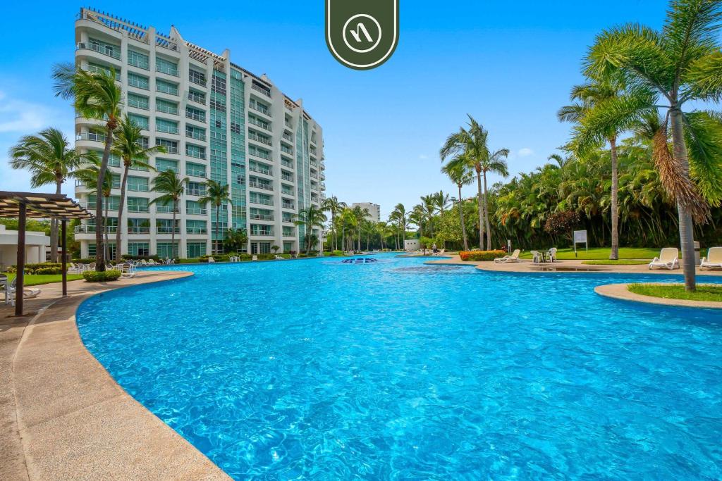 a large swimming pool in front of a building at Stylish 2 BR Condo - Pools - Golf - Membership in Jarretadera