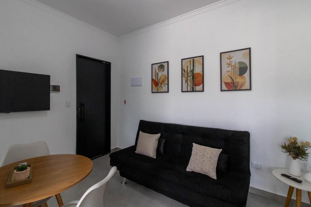 a living room with a black couch and a table at 0804 Orquídea Studio Próx GRU e Estação Cecap in Guarulhos