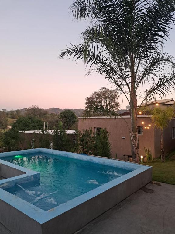 a swimming pool in a yard with a palm tree at Chalé Zarinha I in Serra Negra