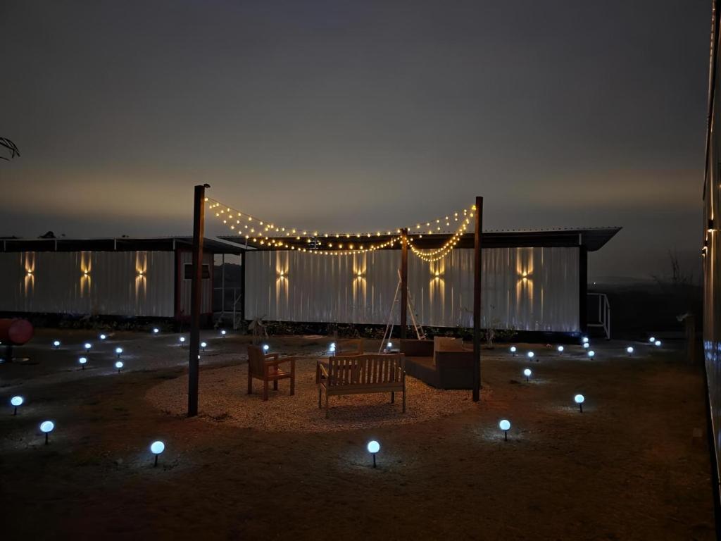 Cabanas do Rancho - Lazer & Eventos em São Roque في ساو روكي: فناء مع مقعد وأضواء في الليل