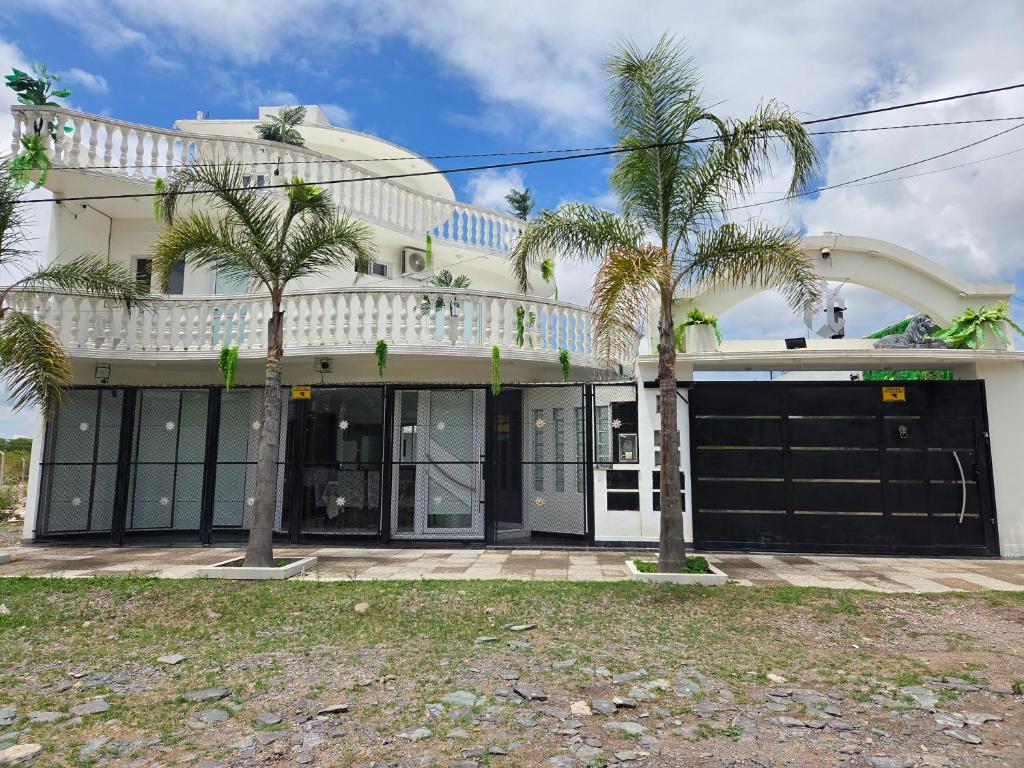a white house with palm trees in front of it at Alisos Suite FC in El Ceibal
