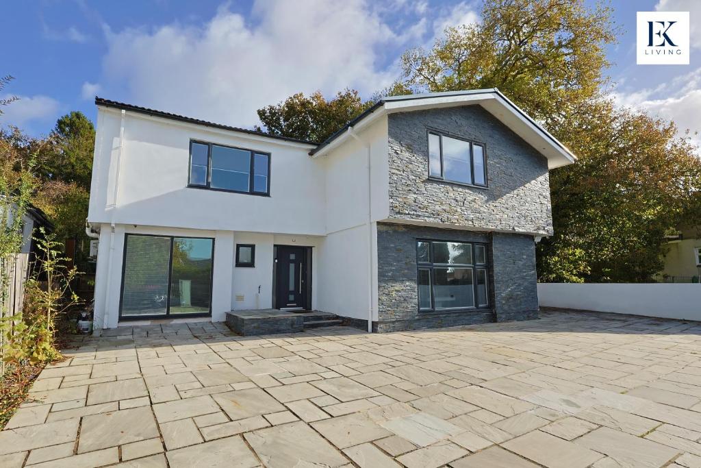 ein großes weißes Haus mit einer Steinzufahrt in der Unterkunft Luxury Group Stay With Bar, 80-inch TV and Parking - Sleeps 10 - By EKLIVING 