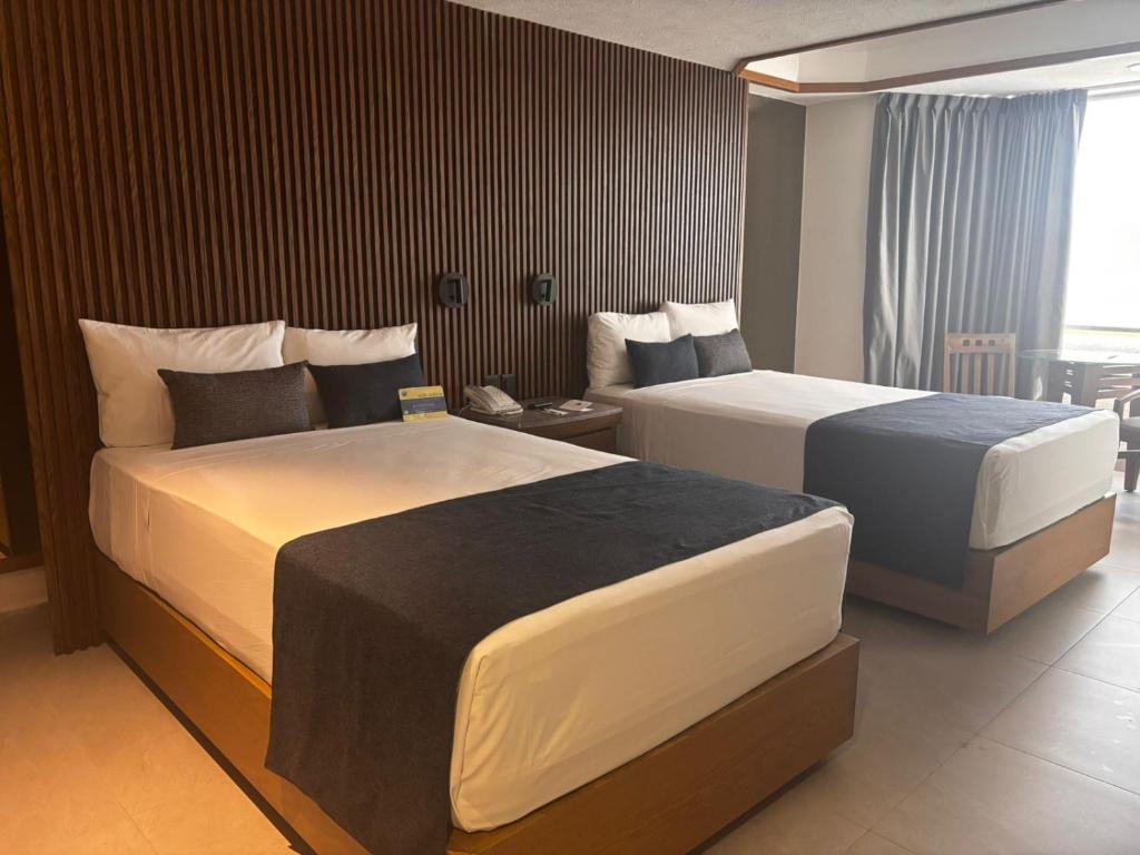 a hotel room with two beds in a room at Hotel Guadalajara Plaza Ejecutivo in Guadalajara