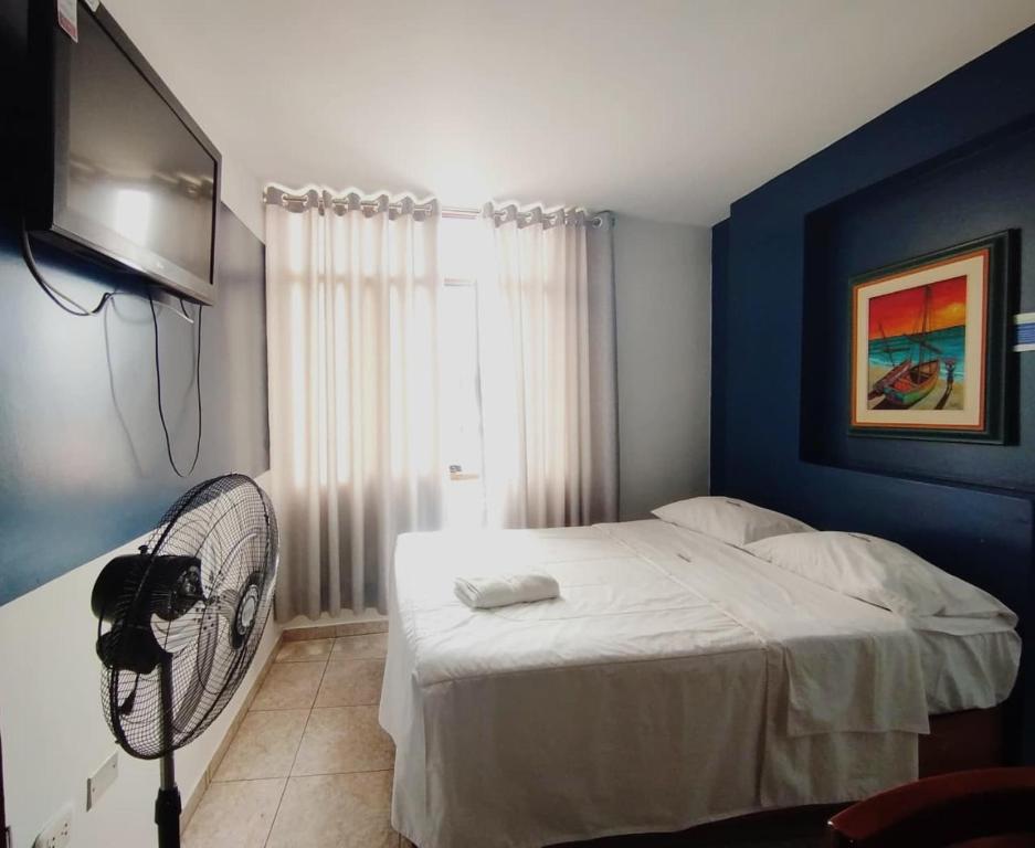 a bedroom with a white bed and a blue wall at Hotel JORGE CHAVEZ in Trujillo