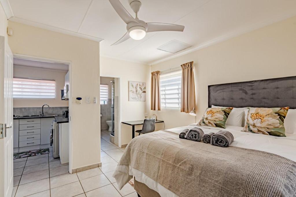 Un dormitorio con una cama grande con ventilador de techo. en Upstairs at 47, en Centurion