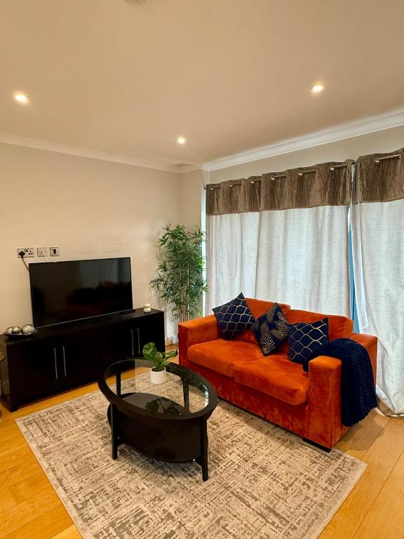 ein Wohnzimmer mit einem orangenen Sofa und einem Couchtisch in der Unterkunft Charming Ensuite Retreat in a Premier Location in Brentford