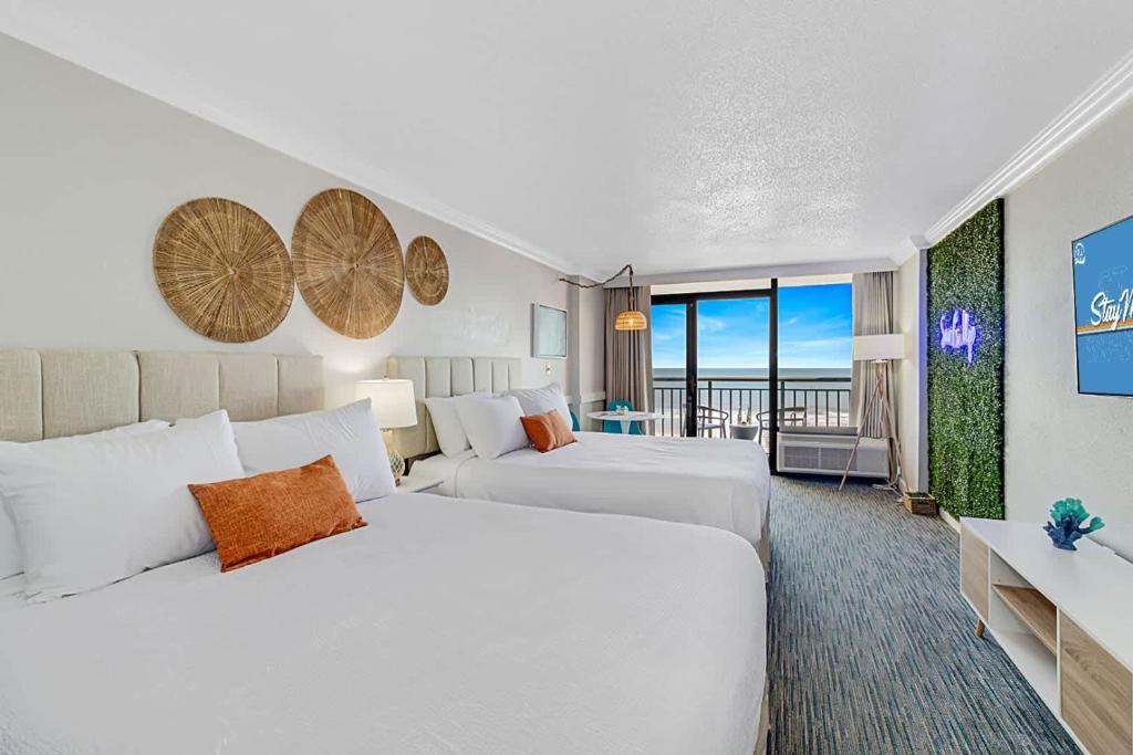 a hotel room with two beds and a balcony at Surf Pavilion by StayMareni - Neon 2 Queen Beds Suite in Myrtle Beach
