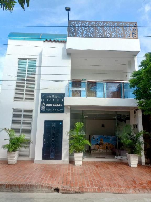 a white building with potted plants in front of it at Hotel Santa Bárbara Mompox in Mompos