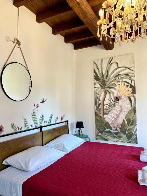 a bedroom with a red bed with a painting on the wall at Chez Madame in Ferrara