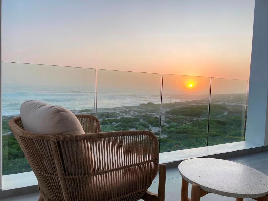 een kamer met een stoel, een tafel en een raam bij Ocean Dream Beach Villa in Yzerfontein