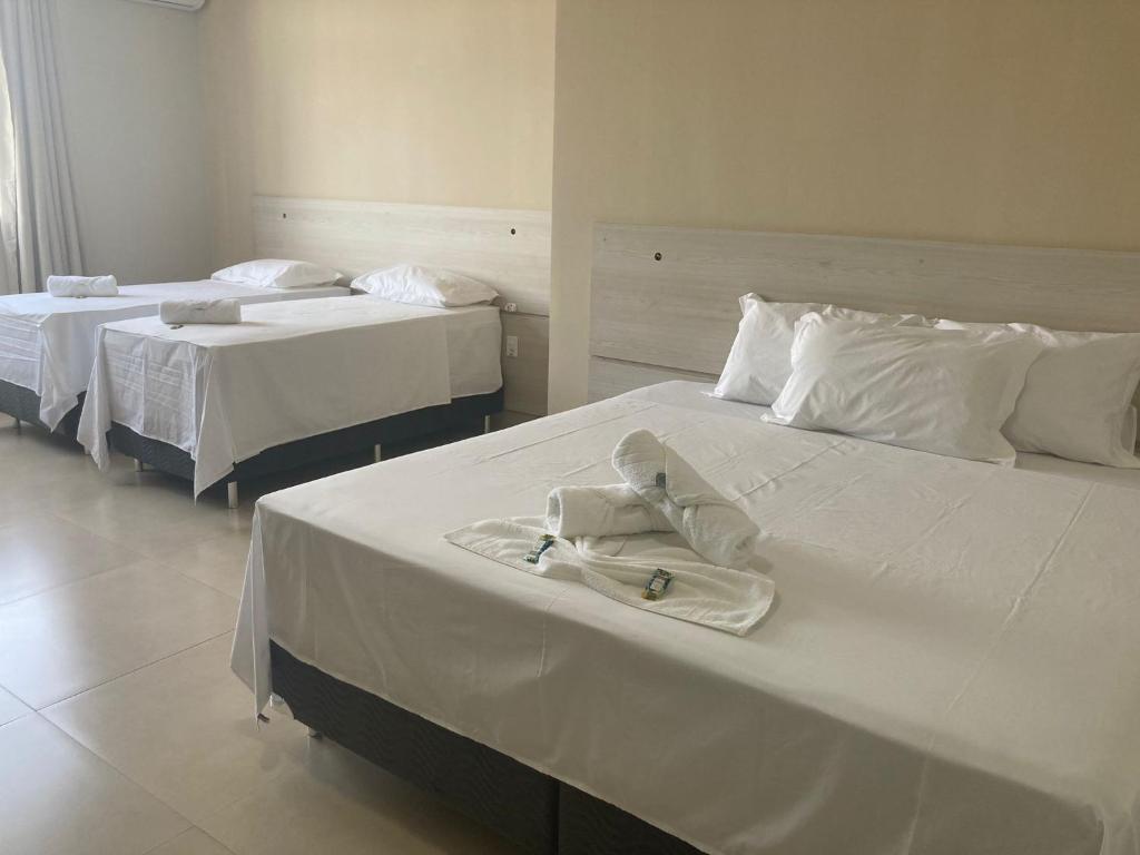 two beds with white sheets and a robe on them at Kuri Hotel in Padre Bernardo