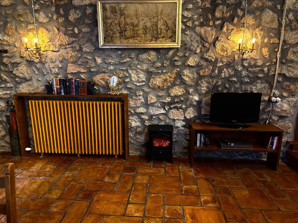 a room with a stone wall with a fireplace and a television at Mas del Drac in Castellví de la Marca