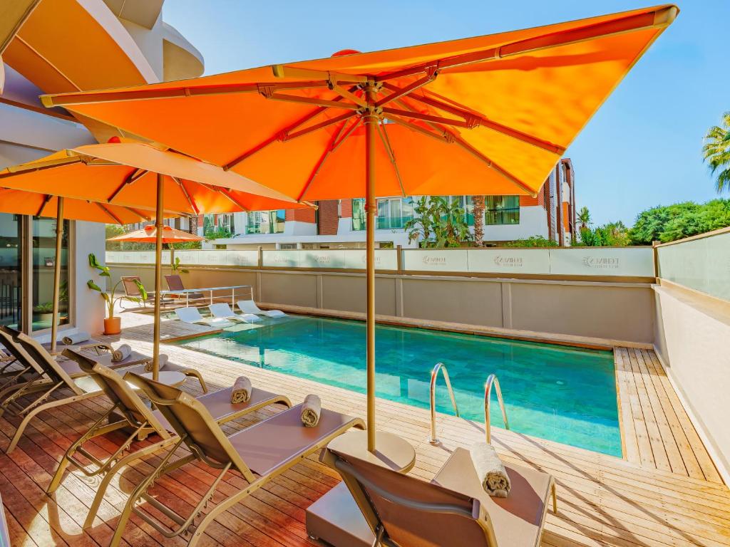 a swimming pool with chairs and umbrellas on a building at Echinus Blue Hotel in Antalya